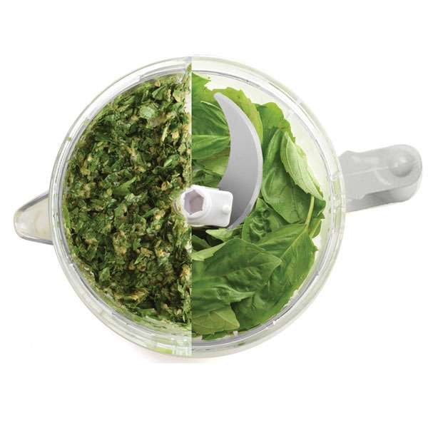 top view of small food processor with half chopped basil and half whole leaf basil