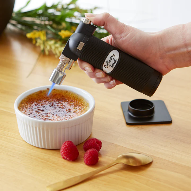 culinary food torch for creme brulee scorching custard in ramekin next to raspberries