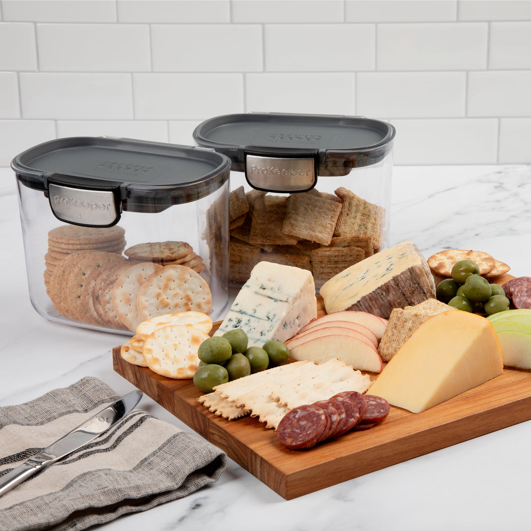 plastic airtight food storage containers with crackers next to charcuterie