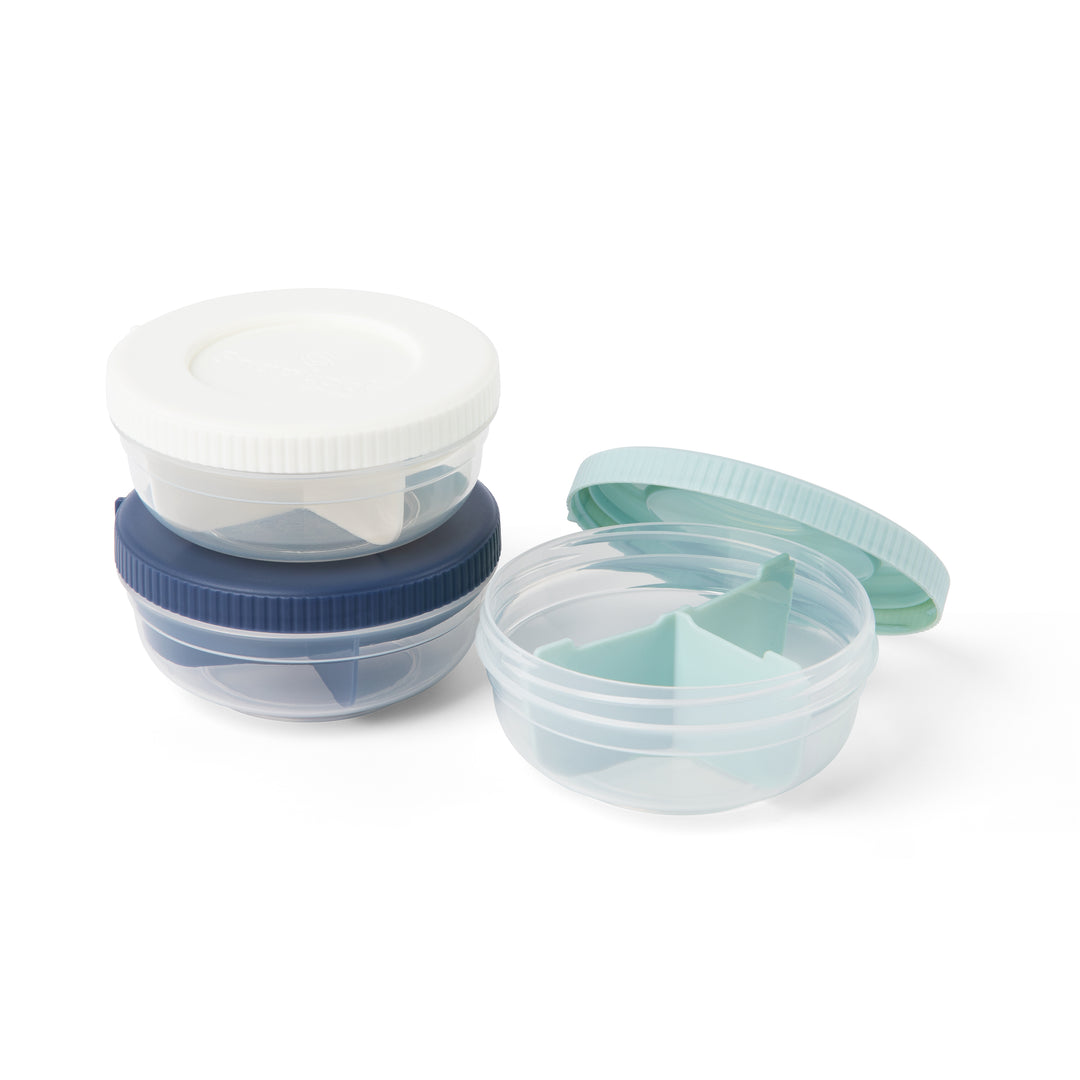 three empty plastic stackable food storage containers for snacks in navy, mint, and white, with navy and white containers in stack and mint container to the side with lid popped off to reveal three compartments and divider inside