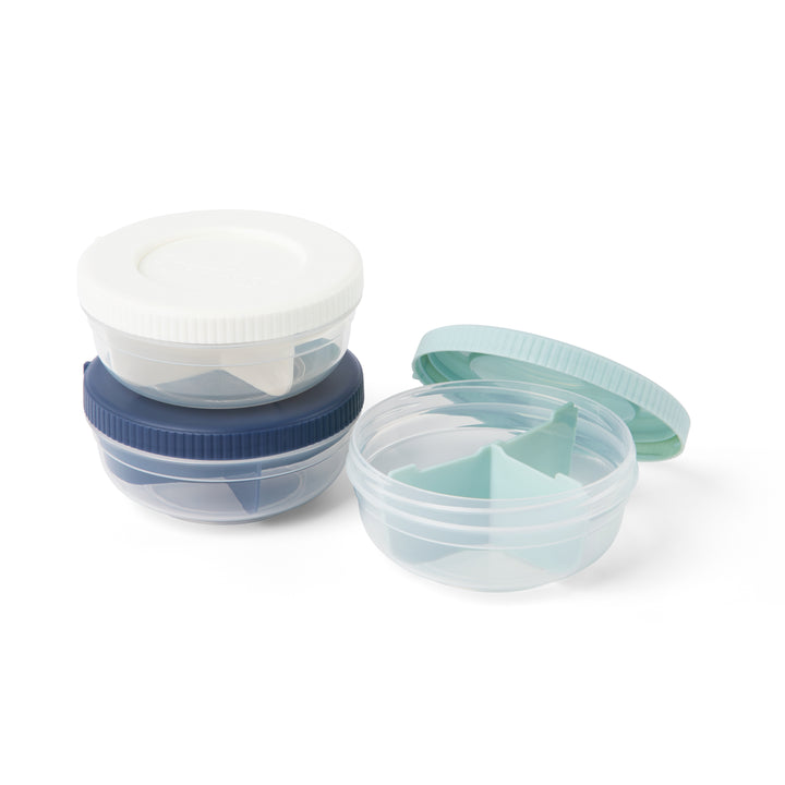 three empty plastic stackable food storage containers for snacks in navy, mint, and white, with navy and white containers in stack and mint container to the side with lid popped off to reveal three compartments and divider inside