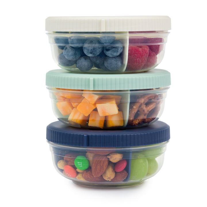 three plastic food storage containers for snacks with snacks inside stacked on top of each other, in navy, mint, and white colors