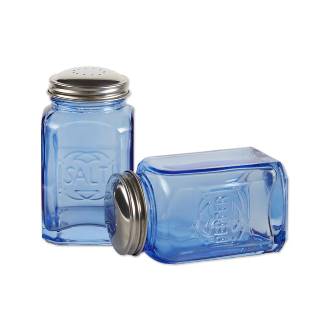 empty blue glass salt and pepper shakers with pepper shaker laying on its side