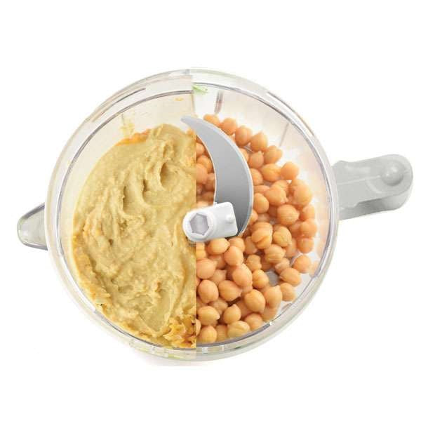 top view of small food processor chopper with half hummus and half whole chickpeas