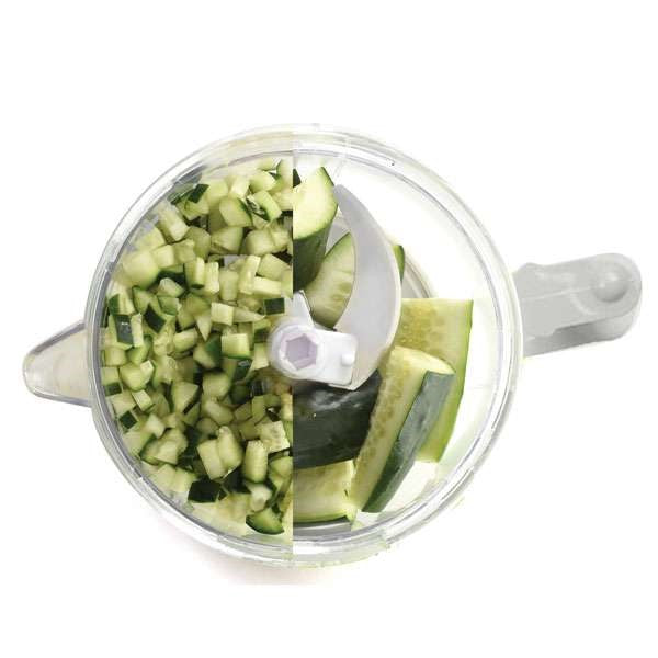 top view of small food processor chopper with half diced cucumbers and half cucumber pieces