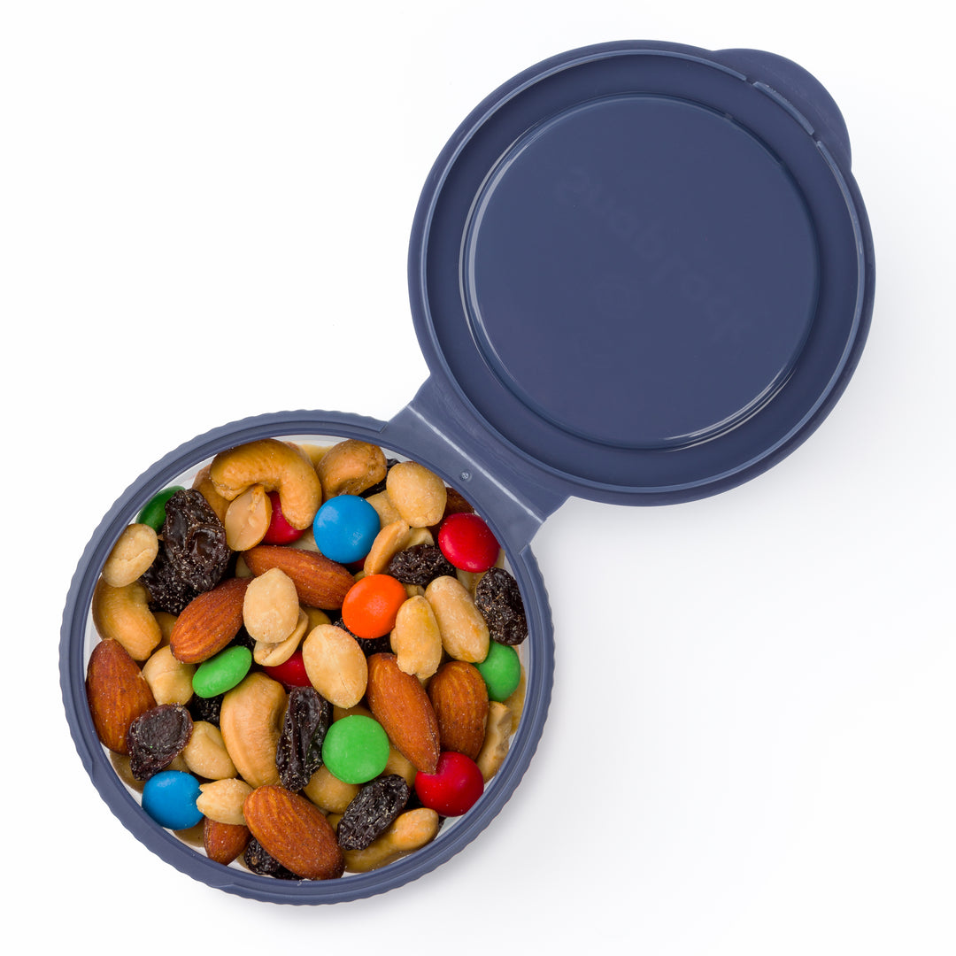 top view of small navy blue snack container with lid open revealing trail mix inside