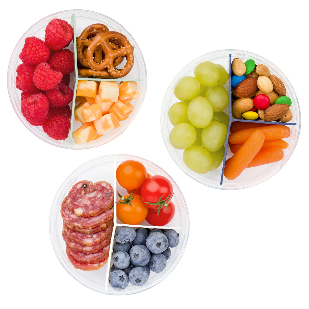 top view of three plastic food storage containers for snacks with lids off and a variety of snacks inside, including fruit, trail mix, cheese, and veggies