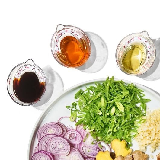 three mini measuring cups with ounces markings and different liquids with vegetable plate